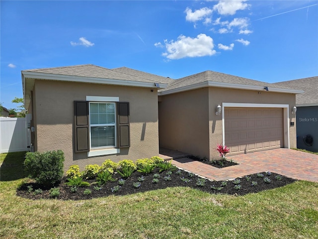 view of front facade featuring a front yard, stucco siding, decorative driveway, and an attached garage
