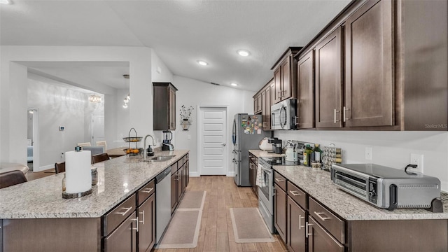 kitchen with dark brown cabinetry, appliances with stainless steel finishes, a sink, light wood-type flooring, and a peninsula