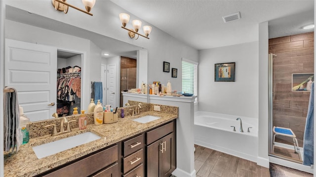 full bathroom featuring visible vents, wood finished floors, a shower stall, and a sink