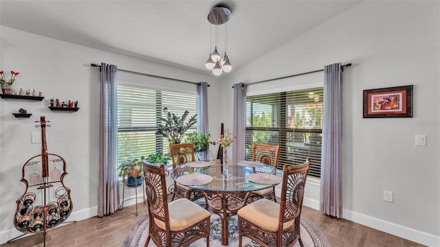 dining area with light wood-style flooring, vaulted ceiling, and baseboards