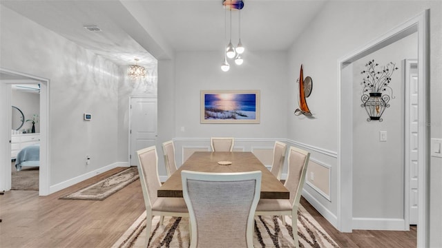 dining space with baseboards, wood finished floors, and an inviting chandelier