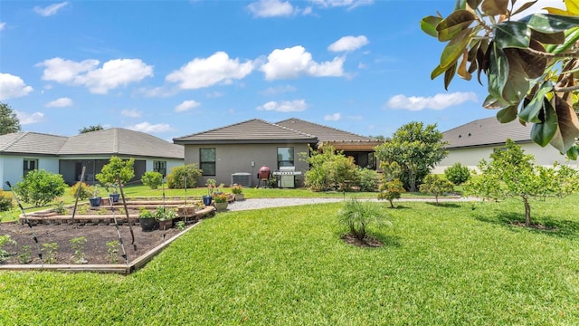back of house featuring stucco siding, a yard, a garden, and central AC