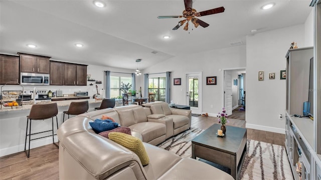 living area with recessed lighting, light wood-style floors, ceiling fan, baseboards, and lofted ceiling