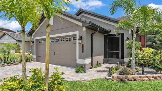 view of front of house featuring a garage, a tile roof, stucco siding, and driveway