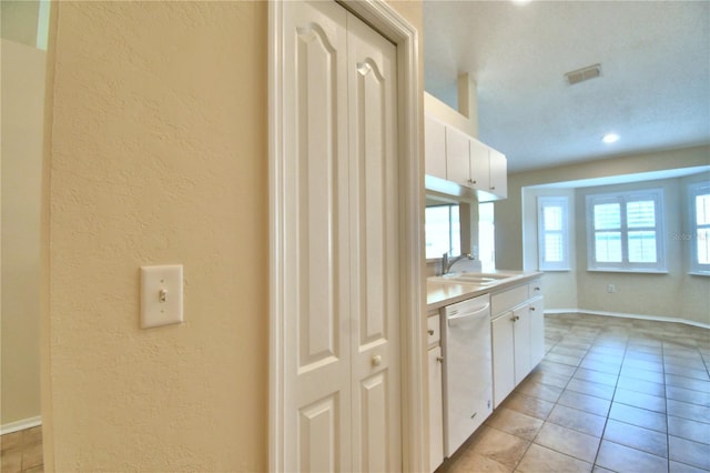 3430 Hilson Dr, Lakeland, FL 33812 - kitchen featuring white cabinets, light countertops, a sink, a textured wall, and dishwasher