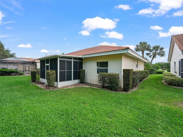 530 Greenway Dr, Lake Wales, FL 33898 - rear view of house with a sunroom, a lawn, stucco siding, and a tile roof