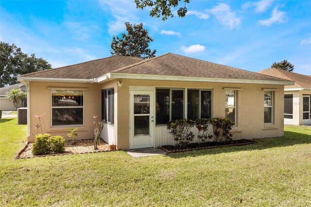 284 Lake Suzanne Dr, Lake Wales, FL 33859 - back of house with stucco siding, central AC, a shingled roof, and a lawn