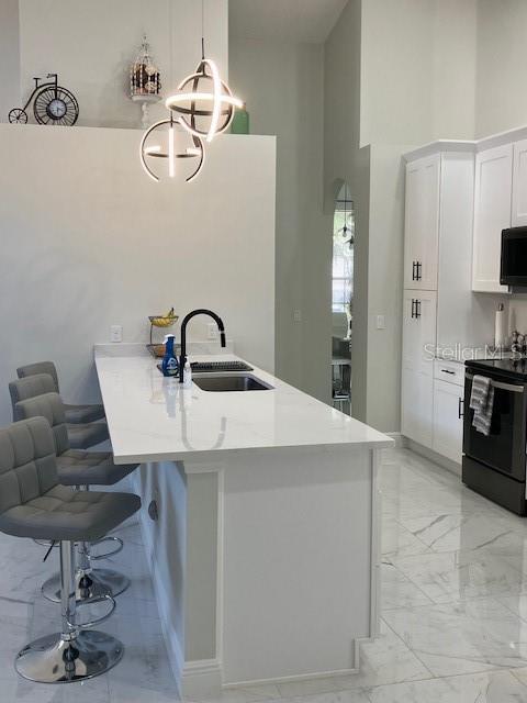 1681 Waterview Loop, Haines City, FL 33844 - kitchen with black appliances, light marble finish flooring, a sink, a breakfast bar area, and a chandelier