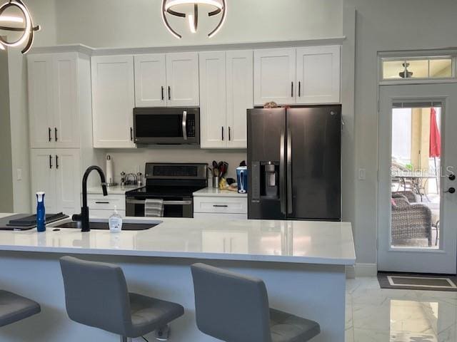 1681 Waterview Loop, Haines City, FL 33844 - kitchen featuring stainless steel appliances, a sink, light marble finish flooring, white cabinets, and a breakfast bar
