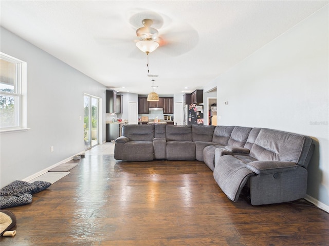 living area with wood finished floors, a ceiling fan, and baseboards
