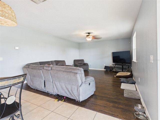 living area with a ceiling fan, light wood-style flooring, and baseboards
