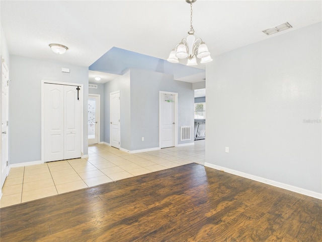 empty room with an inviting chandelier, visible vents, baseboards, and light wood-style floors