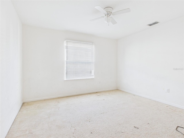 carpeted empty room with baseboards, visible vents, and ceiling fan