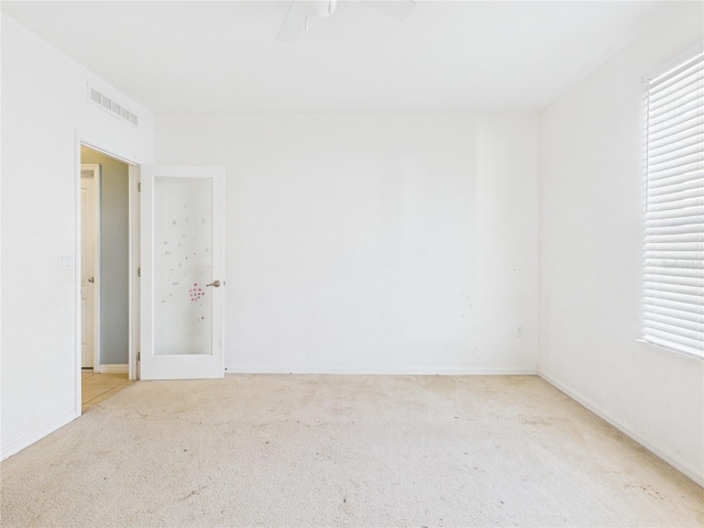 spare room with baseboards, visible vents, ceiling fan, and carpet