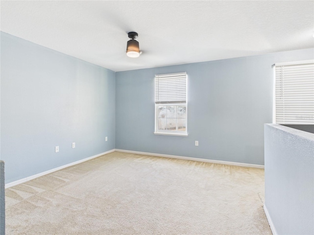 carpeted empty room featuring baseboards