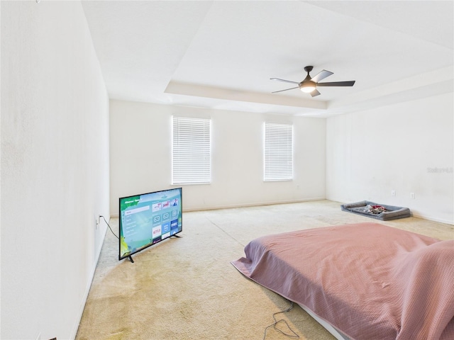 carpeted bedroom featuring a raised ceiling and ceiling fan