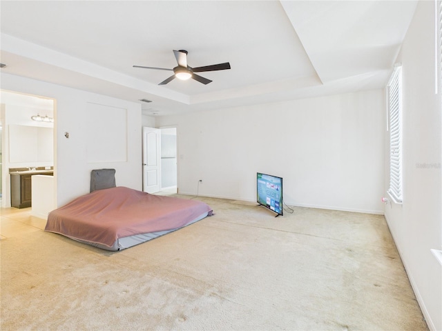 carpeted bedroom featuring visible vents, a raised ceiling, ensuite bath, and baseboards