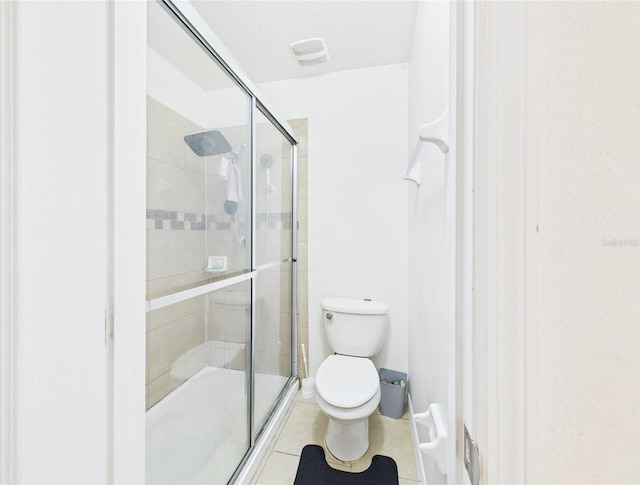 bathroom featuring toilet, tile patterned flooring, and a shower stall
