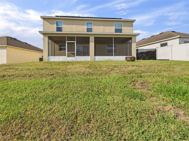 back of property with stucco siding, fence, a yard, and a sunroom
