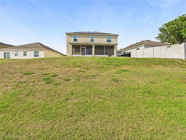 back of property with a sunroom, a lawn, and fence