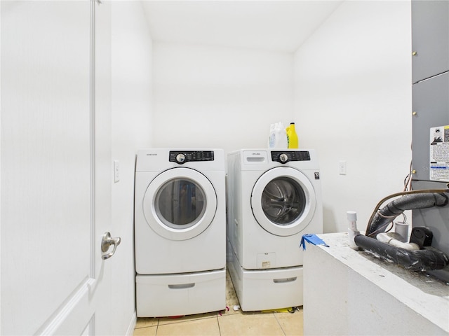 washroom with light tile patterned floors, washing machine and clothes dryer, and laundry area