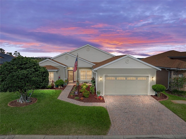 4081 Dunmore Dr, Lake Wales, FL 33859 - view of front of house featuring a garage, decorative driveway, a yard, and stucco siding