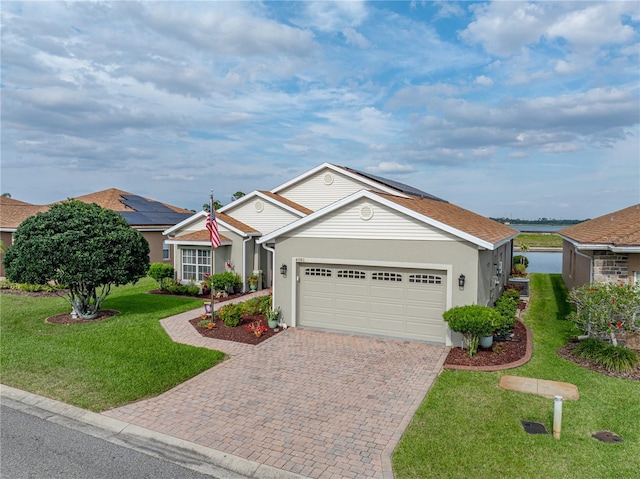 4081 Dunmore Dr, Lake Wales, FL 33859 - view of front of house featuring decorative driveway, a garage, a front lawn, stucco siding, and solar panels