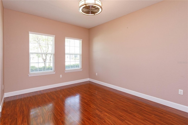 unfurnished room with baseboards and dark wood-style floors
