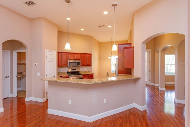 kitchen featuring wood finished floors, visible vents, baseboards, pendant lighting, and appliances with stainless steel finishes