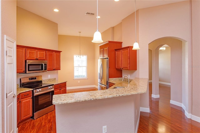 kitchen with stainless steel appliances, wood finished floors, a sink, and high vaulted ceiling