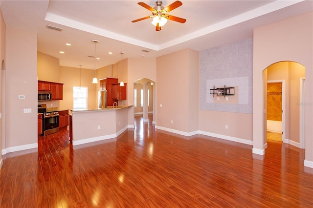 unfurnished living room with arched walkways, visible vents, a ceiling fan, and dark wood-style flooring