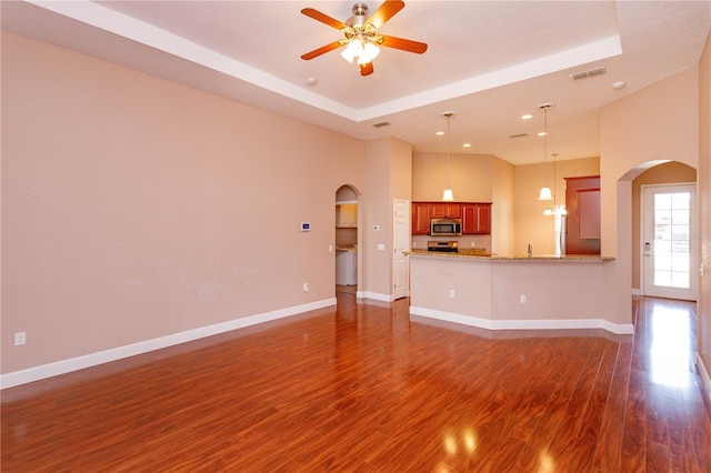 unfurnished living room featuring arched walkways and baseboards