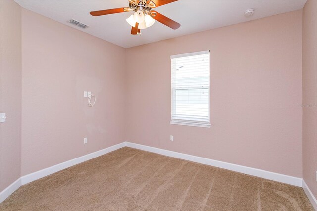 empty room with light carpet, a ceiling fan, visible vents, and baseboards