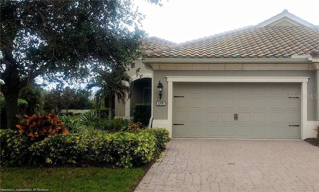 1375 Backspin Dr, Englewood, FL 34223 - view of side of home with stucco siding, a tile roof, an attached garage, and decorative driveway
