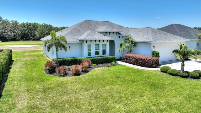 view of front of house with an attached garage, roof with shingles, stucco siding, and a front yard