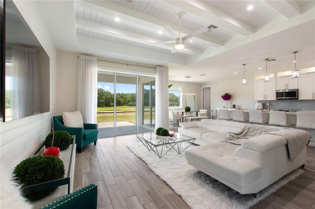 living area with beamed ceiling, a ceiling fan, recessed lighting, and wood finished floors