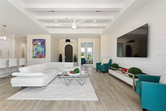 living room with visible vents, wood walls, beamed ceiling, light wood-style floors, and ceiling fan