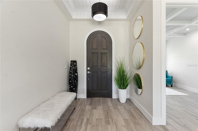 entryway with crown molding, arched walkways, baseboards, and light wood-type flooring