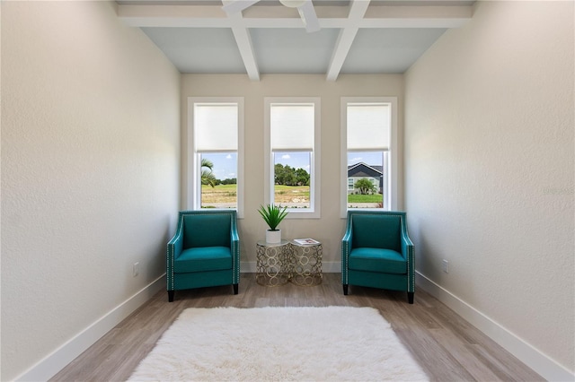 living area with wood finished floors, beam ceiling, a healthy amount of sunlight, and coffered ceiling