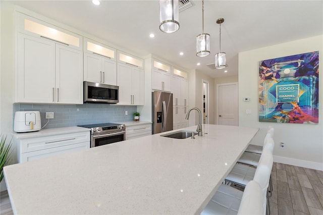 kitchen with baseboards, a spacious island, a sink, light wood-style flooring, and appliances with stainless steel finishes
