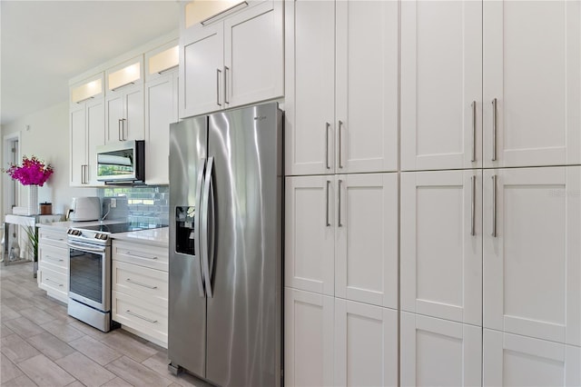 kitchen with decorative backsplash, glass insert cabinets, light countertops, white cabinetry, and stainless steel appliances