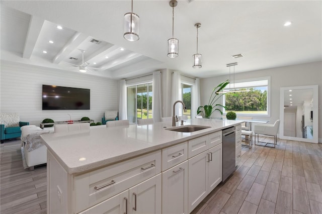 kitchen featuring visible vents, open floor plan, white cabinetry, a sink, and light wood finished floors