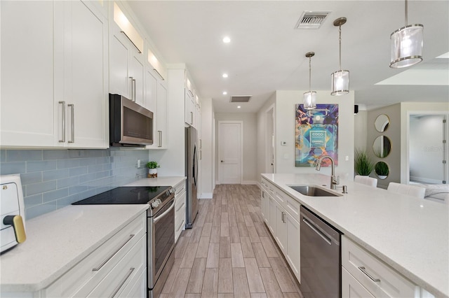 kitchen with stainless steel appliances, visible vents, decorative backsplash, and a sink