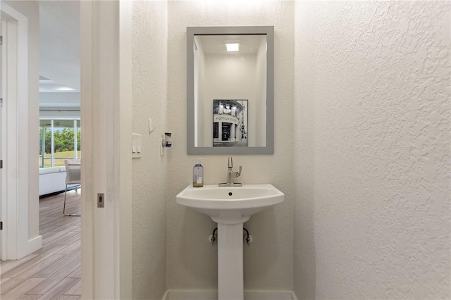 bathroom featuring baseboards, a textured wall, and wood finished floors