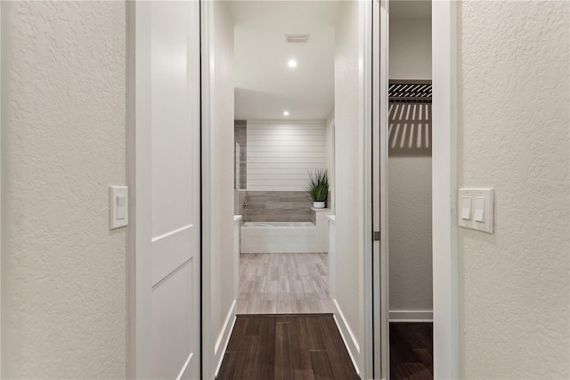 corridor with baseboards, a textured wall, recessed lighting, and wood finished floors