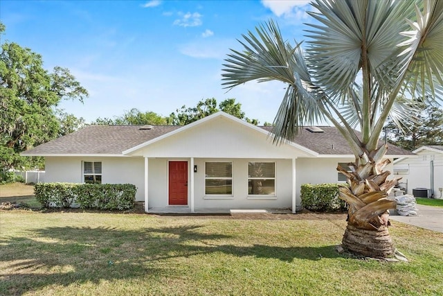 view of front of home with stucco siding, cooling unit, a shingled roof, and a front lawn