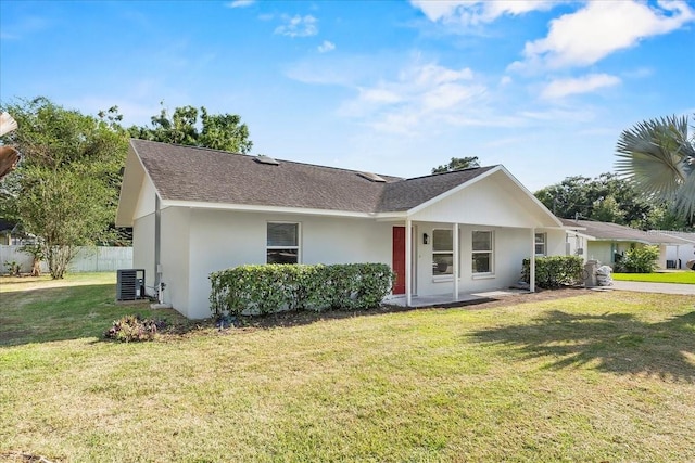 ranch-style home with fence, a front yard, cooling unit, roof with shingles, and stucco siding