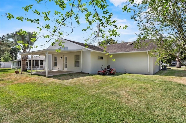 back of property with a yard, a patio, stucco siding, and a carport