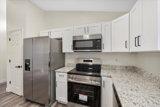 kitchen with light wood finished floors, white cabinets, vaulted ceiling, and stainless steel appliances