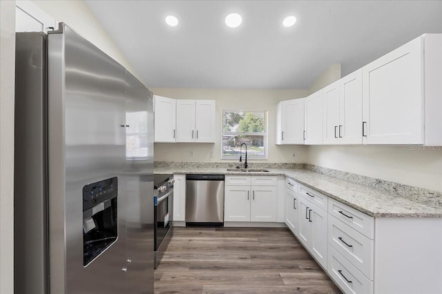kitchen featuring a sink, white cabinets, stainless steel appliances, and wood finished floors